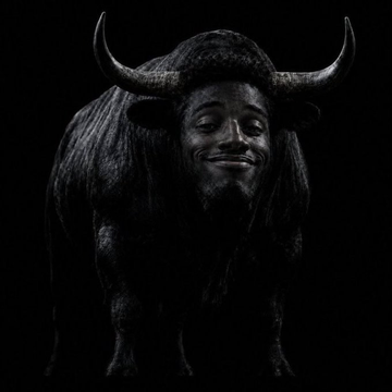 A black bull with a human face smiles against a dark background, symbolizing bullish momentum. This ties to the post's theme of two memecoin runners—$WORLD and $ANSEM—riding strong on Solana, where early holders saw explosive gains.