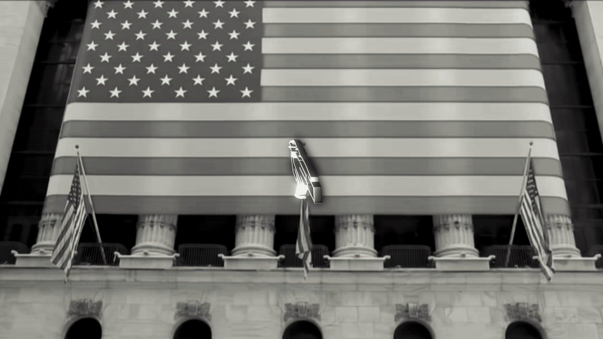 The image features a large American flag displayed prominently above an office building's entrance. The flag is positioned at the top of the building, with its four corners pointing towards the sky. Below the flag, there are several smaller flags fluttering in the breeze, adding to the overall patriotic atmosphere. The image also includes text that reads "Focus on what is in the image and how it relates to the post." This suggests that the focus should be on the American flag and its significance as a symbol of national pride and unity.