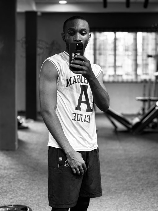 A black-and-white mirror selfie of a young man wearing a sleeveless 'Alabama A' jersey and dark shorts in what appears to be a gym setting.