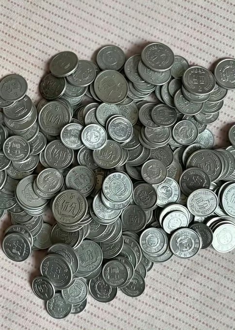 A scattered pile of silver-colored metallic tokens or coins, many bearing a 'W' logo, resting on a textured white surface.