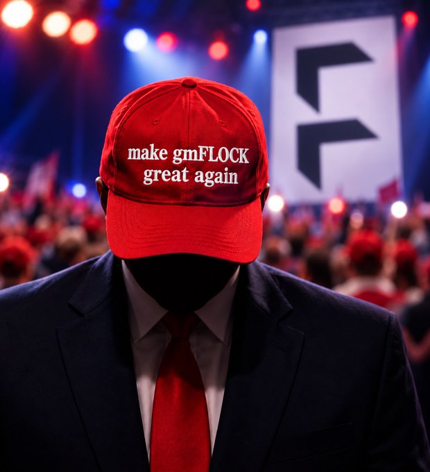 A figure in a dark suit and red tie wearing a red MAGA-style hat that reads 'make gmFLOCK great again', standing before a crowd with a rally backdrop displaying a logo.