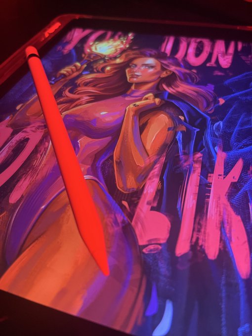 An orange stylus rests on a digital drawing tablet displaying a vibrant, comic-style illustration of a woman, with the text "YOU DON'T LIKE" visible in the background.