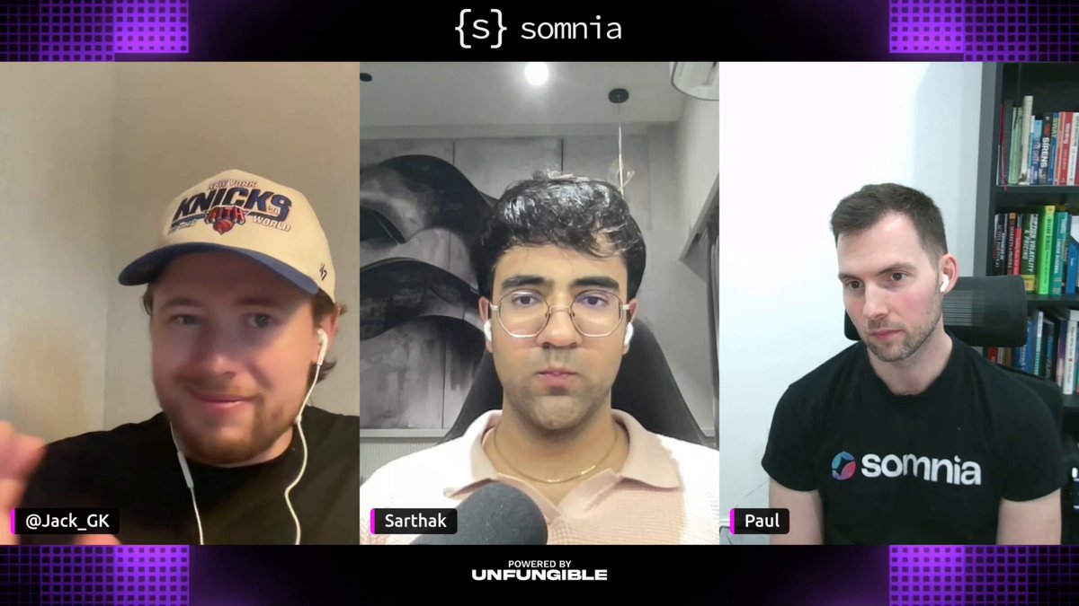 The image shows three men wearing baseball caps, with one man holding a microphone while another two men look on. The background features purple and white colors, which could be related to the content displayed on the screen or the overall design of the image.