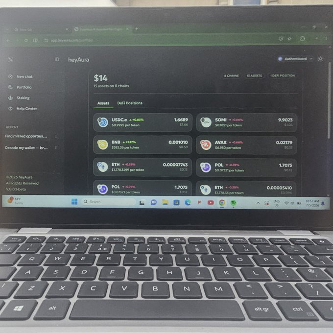 A laptop displays the heyAura portfolio dashboard showing a $14 total balance across 15 assets on 8 chains, including USDC ($1.66), SOMI ($5.66), BNB ($0.35), AVAX ($0.10), and various ETH and POL positions, illustrating the platform's ability to consolidate a multi-chain wallet overview in a single unified view.