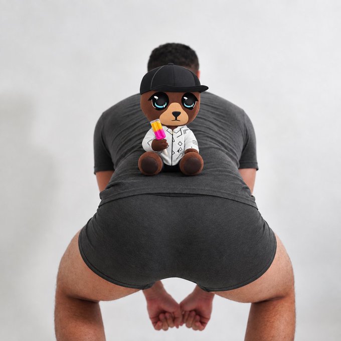 A man squats with his back to the camera, while a cartoon brown teddy bear wearing a black cap and holding a popsicle is digitally placed on the back of his shirt.
