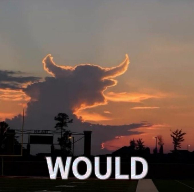 A dramatic sunset photo over a sports field showing a cloud formation that resembles a horned bull or ox head silhouetted against orange and purple sky, with the text 'WOULD' overlaid at the bottom.