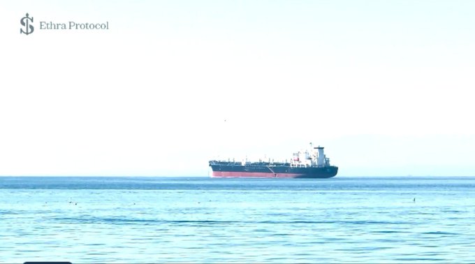 A photo of a cargo ship sailing on a calm blue sea, with the 'Ethra Protocol' logo visible in the top left corner.