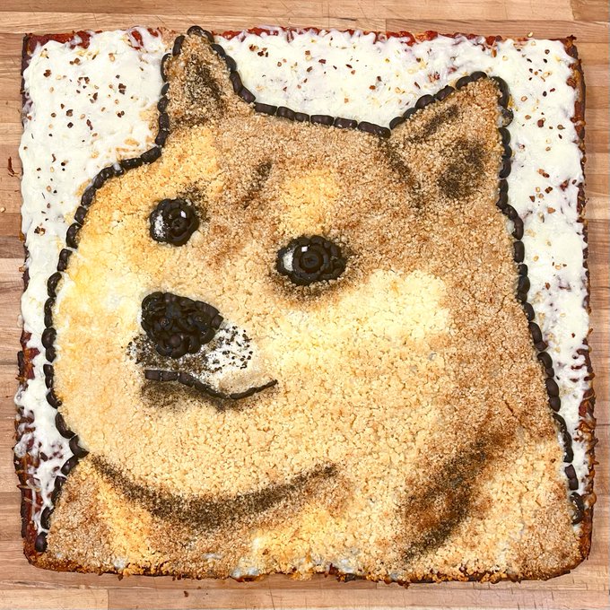 A square cake decorated with a detailed image of a Shiba Inu dog's face, outlined in chocolate, resting on a wooden surface.