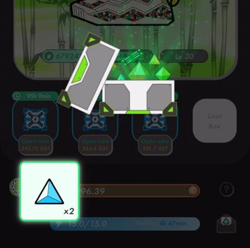 The image shows a close-up view of an open box with a green triangular object inside, which appears to be a gemstone or crystal. The box has a white lid that is slightly open, revealing the contents within. The background of the image features a cartoon character and text elements related to the post on social media.