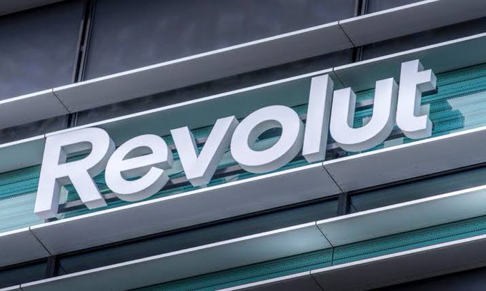 A close-up of a metallic 'Revolut' sign mounted on the glass and steel facade of a building.