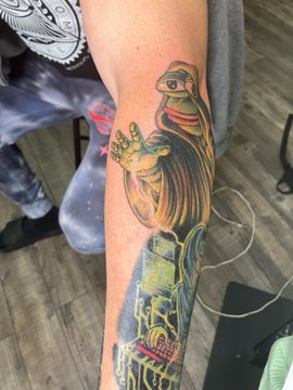 A colorful tattoo on an arm depicting a giraffe wearing sunglasses and a red shirt, alongside other illustrated figures.