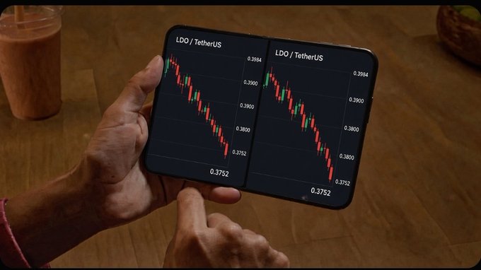 A person holds a folding smartphone displaying a candlestick chart for the LDO/TetherUS trading pair, showing a price around 0.3752, with a coffee drink visible in the background.