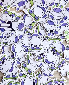 A pile of cartoon stickers featuring a white character with purple accents riding green skateboards, matching the "sticky Ronnies" mentioned in the post about printing over 100 stickers for a frame-by-frame animation project.