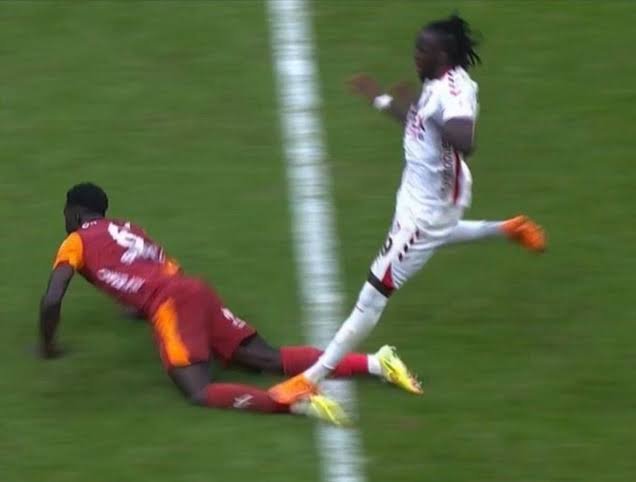 A soccer match shows a player in a maroon and yellow kit sliding on the grass while an opposing player in white sprints away, with visible text "OMAN" on the back of the maroon jersey and the number "54" on the white kit.

The image appears to illustrate the post's theme of "red" — likely referring to a red card or red-themed jersey incident in soccer, mocking those who previously denied or downplayed the obvious evidence now being vindicated, much like paying out early after previously betting against it.