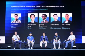 The image features a group of five men sitting around a table, likely participating in a panel discussion or conference. They appear to be engaged in conversation about stablecoins, wallets, and the new payment stack. The backdrop for this gathering is a large screen displaying the names of the speakers and attendees, as well as some text related to the event.