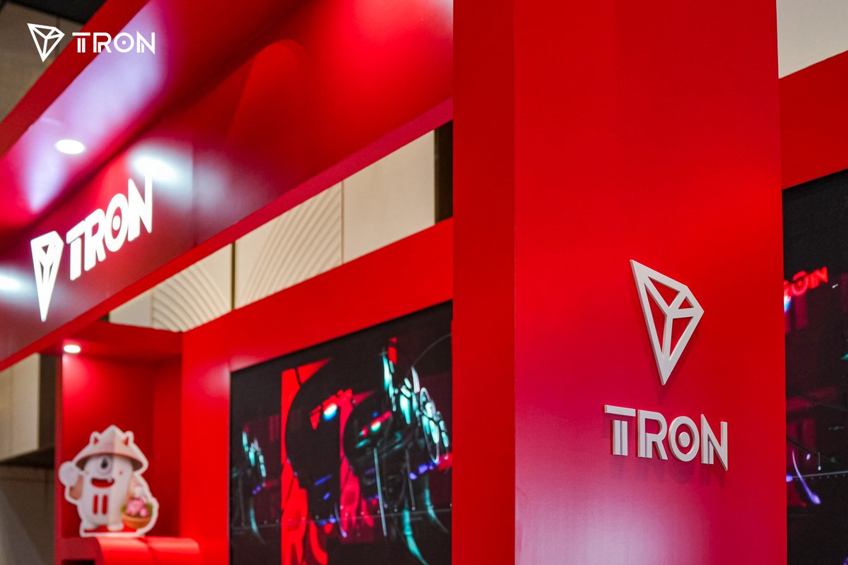 A vibrant red TRON-branded booth featuring the "TRON" logo and diamond-shaped emblem, with a Phishing Bao mascot cutout visible at the entrance, representing the platform's presence as a Diamond Sponsor at the Conviction 2026 conference. The sleek, illuminated branding creates a striking visual showcase for engaging with Web3 builders and developers.
