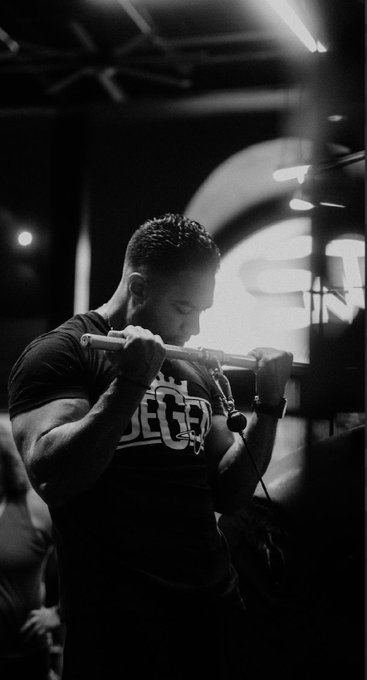 A man performs a cable tricep pushdown in a gym, with his "ECHO" branded t-shirt visible under the dramatic lighting. The intense workout embodies the post's theme of "Strong body/strong mind," highlighting the mental discipline required alongside physical exertion.