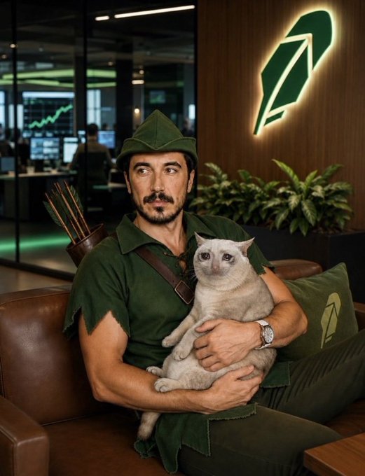 A man dressed as Robin Hood—complete with a green tunic, feathered cap, and a quiver of arrows—holds a gray cat on his lap in what appears to be a Robinhood office, with the company's feather logo illuminated on the wall behind him. The post "ROBINHOOD CHAIN SUPERCYCLE 🚀🚀🚀" plays on the Robinhood branding, evoking the idea of a trading boom or bull run tied to the platform.