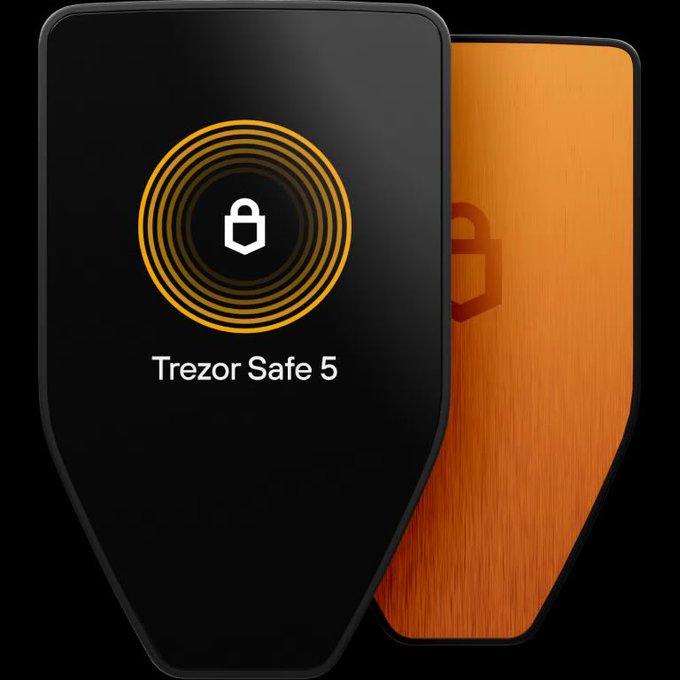 Two Trezor Safe 5 hardware wallets are displayed side by side—one with a black front showing the orange Trezor logo and a padlock icon, and the other revealing an orange metallic backplate with an embossed "B" logo. The image relates to the post by highlighting Trezor's hardware security amid criticism of Coinkite's Coldcard entropy issues, as the Trezor Safe 5 is positioned as a more secure alternative.
