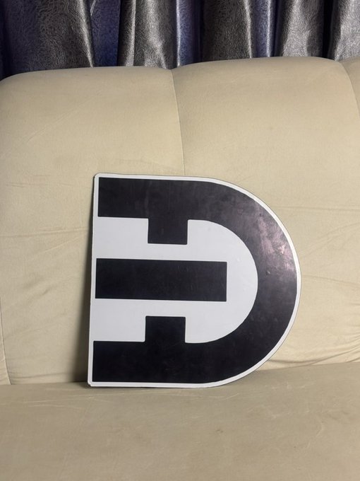 A large stylized "D" logo (representing $DTEC) rests on a beige leather couch against dark curtains, visually anchoring the brand behind the post's claim that DTEC represents the next revolutionary step in mobility—following fire, the wheel, and the car—through AI-powered smart cars and DePIN networks.