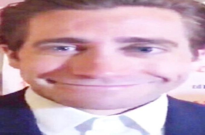 A heavily distorted 'Jim' meme face showing a man in a suit and tie with an exaggerated, stretched smiling expression.