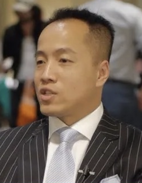 A photo of Harry Yeh, the Quantum Fintech founder who reportedly died after falling from a 30th-floor apartment in Asunción, Paraguay, wearing a pinstripe suit and light-colored tie in what appears to be an event setting.