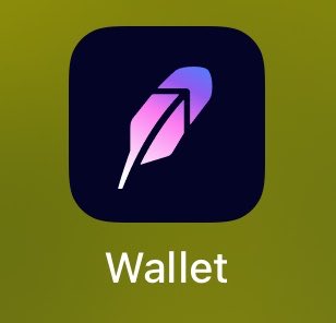 A mobile app icon with a gradient purple and pink feather/leaf logo on a dark rounded square background with the label 'Wallet' beneath it.