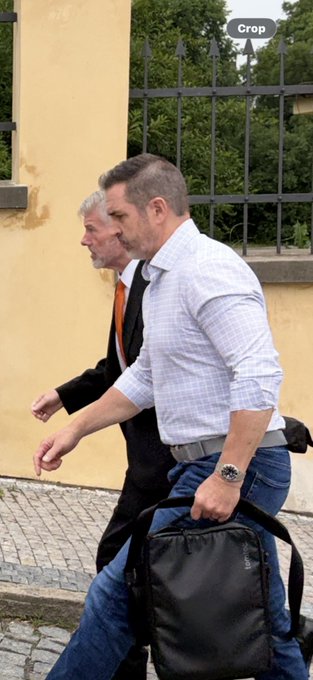 The image shows two men walking down a street while carrying bags. One of them has a black bag over his shoulder, and the other one has a backpack on his back. They are both dressed professionally with ties, suggesting they might be businessmen or professionals attending an event in Prague. The photo also includes text that reads "hey @saylor since you now sell BTC lets meet up in Prague and do OTC sale just for the lore thanks, DMs open". This message seems to be related to a recent online purchase made by one of the men on Bitcoin, possibly indicating their interest in cryptocurrency or an event happening in Prague.