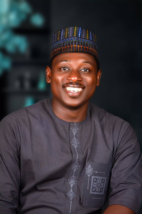 A smiling man wearing a traditional dark embroidered outfit and patterned cap poses against a dark backdrop, projecting a confident and welcoming presence that aligns with the bullish, community-driven spirit of the "$GAYU" cryptocurrency post.