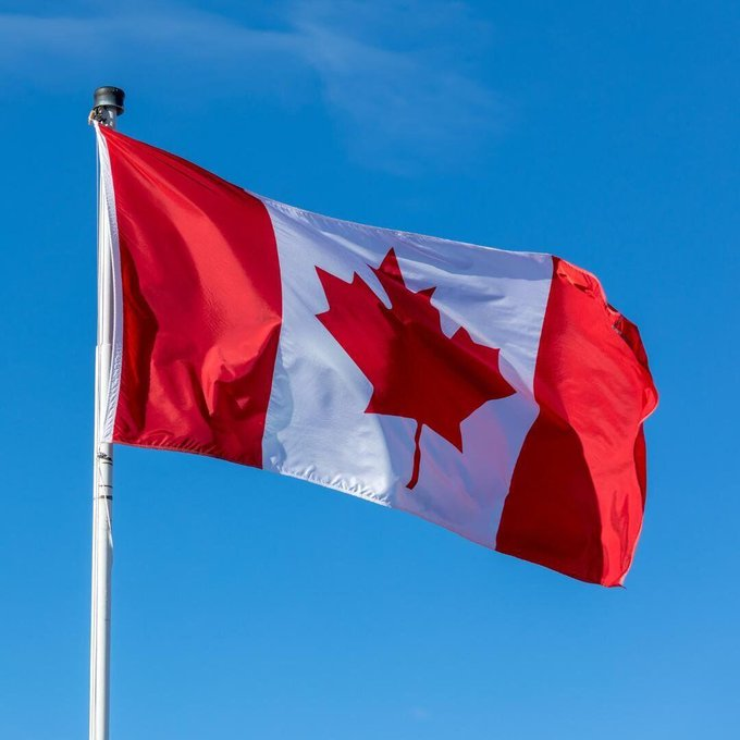 A Canadian flag waves against a clear blue sky, symbolizing the nation behind a new regulatory move that permits banks to place deposits on the blockchain. The image visually represents the country mentioned in the news update about Canada's latest crypto-friendly banking decision.