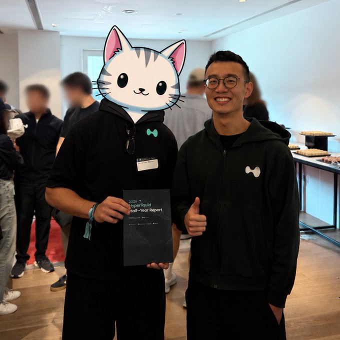 Two people pose at an event, with one holding a document labeled "2020 H1 Hyperliquid Half-Year Report," while the smiling individual on the right (face visible) gives a thumbs-up beside a companion whose face is covered by a cat sticker. The image reflects the post's gratitude toward the Hyperliquid ecosystem community and builders following stops in Seoul and Singapore.