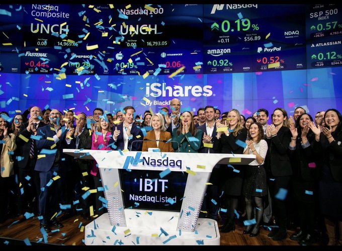 A celebratory Nasdaq event for the iShares Bitcoin Trust (IBIT) by BlackRock, with confetti falling as people clap in front of a stock ticker showing companies like Amazon, PayPal, and Atlassian.