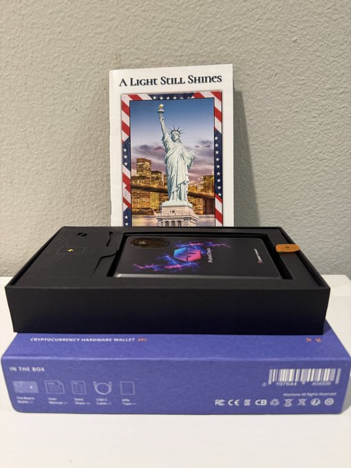 A newly arrived Keystone Pro 3 hardware wallet with PulseChain branding sits on its box, accompanied by an "A Light Still Shines" card featuring the Statue of Liberty. The setup aligns with the post's excitement about testing the wallet alongside the ZKX extension and Web App for potential improvements.