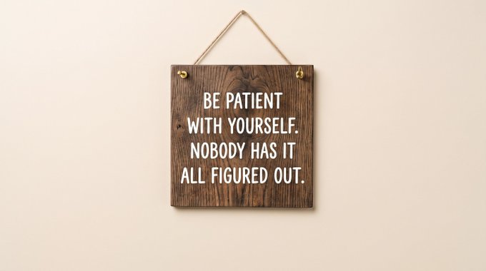 A wooden hanging sign displays the motivational quote 'BE PATIENT WITH YOURSELF. NOBODY HAS IT ALL FIGURED OUT.'