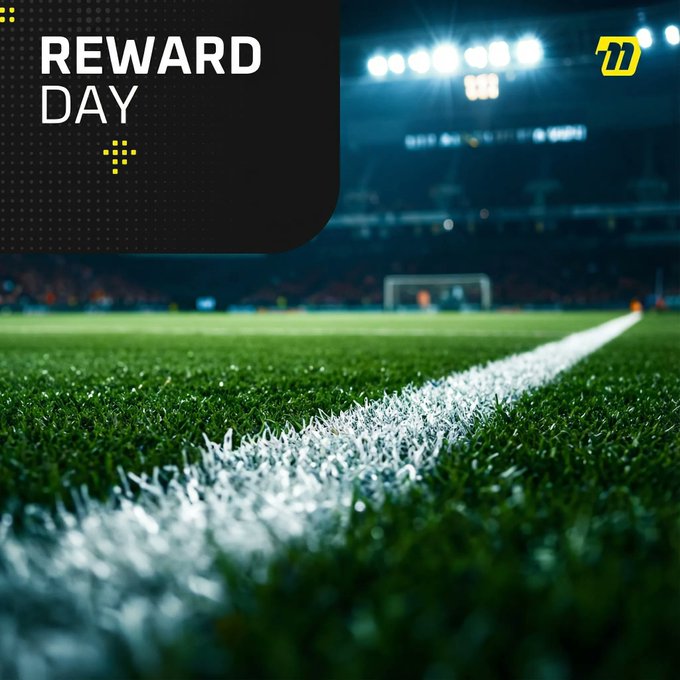 A promotional graphic with 'REWARD DAY' text overlaying a low-angle shot of a green soccer field at night with stadium lights in the background.