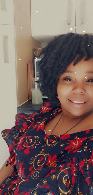 A woman with a bright smile poses in a kitchen, wearing a vibrant red and navy floral-patterned dress, with the caption reflecting her mood of being "hungry for progress and thirsty for creativity"—capturing the warm, optimistic energy behind pursuing new ideas and projects.