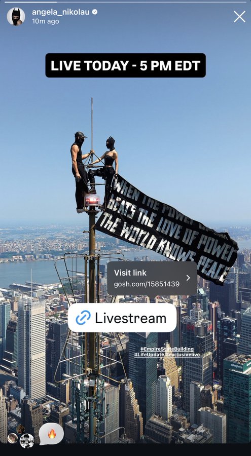 An Instagram story from angela_nikolau promoting a live stream at 5 PM EDT, showing her and a partner performing a stunt atop a skyscraper with a banner reading 'WHEN THE POWER OF LOVE BEATS THE LOVE OF POWER THE WORLD KNOWS PEACE' and a GOSH livestream link.
