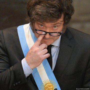 Argentine President Javier Milei wearing the presidential sash, adjusting his glasses while looking toward the camera, with a watermark 'Juan Mabromata/AP'.
