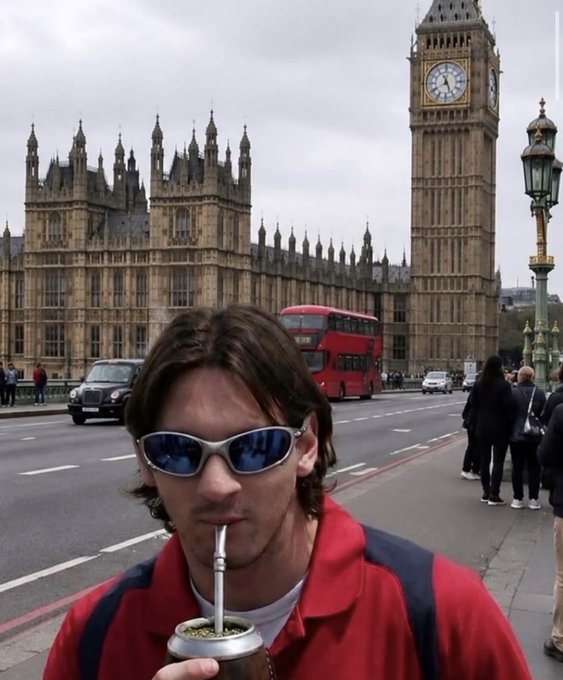 A young man with sunglasses drinking mate through a straw in front of the iconic Big Ben clock tower and a red double-decker bus in London.