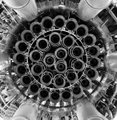 A circular arrangement of metallic rods viewed from above, forming a triskelion or spiral pattern that reflects the geometric principles of the Golden Ratio (1.618), as referenced in the post about the Ripple Logo/Triskelion by Fabian Ruehle.