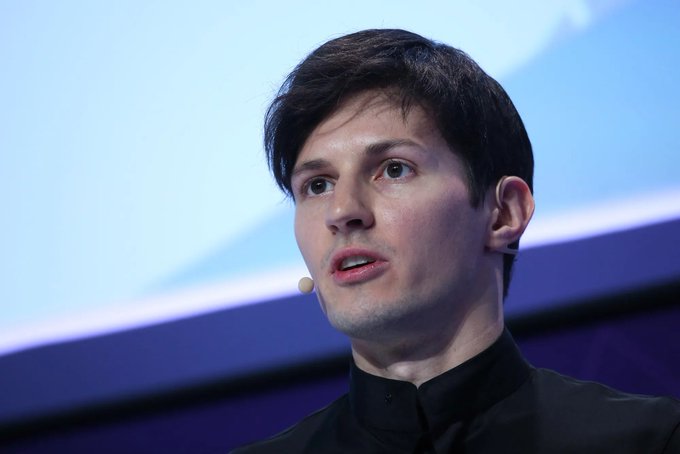 A man with dark hair, wearing a black collared shirt and a small headset microphone, speaks while looking off to the side against a blue background. The image accompanies a post about Pavel Durov, founder of Telegram and VKontakte, referencing the contrast between his entrepreneurial success and the controversial allegations made against him.