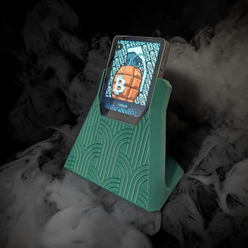 The image shows a green safe or docking station with a white item (likely a smartphone) placed inside of it, sitting on top of a black surface with smoke coming out from underneath. The text below the image states that there is a new product drop for the @Trezor Safe and it's available for sale at the website for $5.99.
