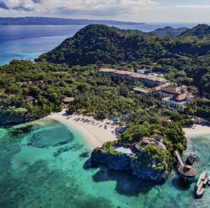 Aerial view of a tropical island resort with white-sand beach, turquoise waters, and lush green hills, reflecting the Boracay Philippines getaway referenced in the XLM Army post celebrating a potential Stellar (XLM) price surge.
