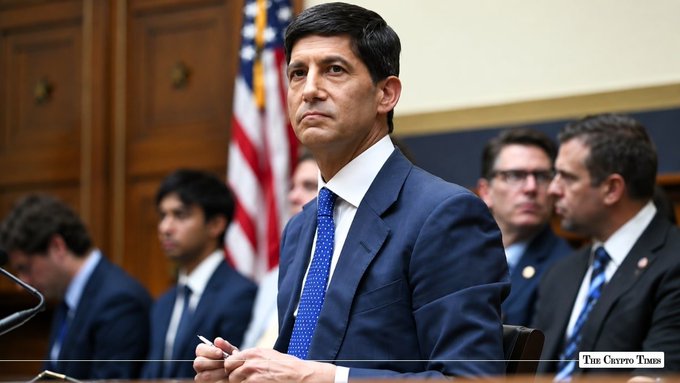 A man in a blue suit sits at a congressional hearing with an American flag in the background, captioned 'The Crypto Times'.