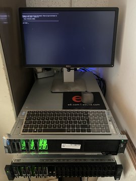 A laptop displaying what appears to be a terminal or command interface sits atop a stack of rack-mounted servers with glowing green lights, with an "E Evernode" branded mousepad visible. The setup visually represents the decentralized node operations referenced in the post, showcasing the physical hardware infrastructure that powers Evernode's distributed data network, akin to modern Bitcoin mining rigs.