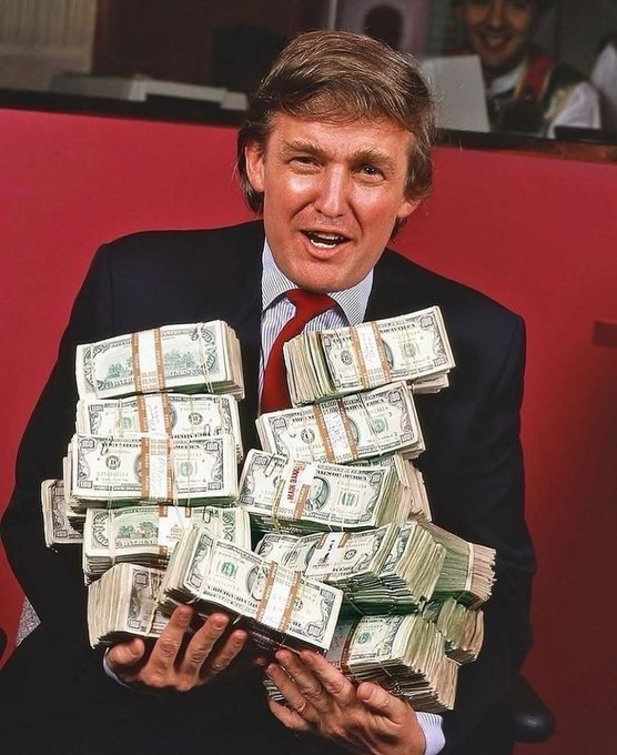 A vintage photo of Donald Trump holding multiple large stacks of bundled US dollar bills.