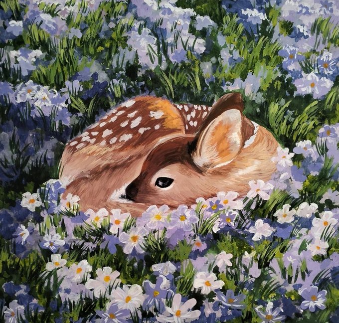 A young fawn with white-spotted brown fur rests curled up among a dense field of small white and lavender flowers, with green grass blades peeking through the blooms.