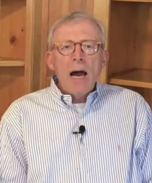 Veteran trader Peter Brandt, seen here wearing a striped button-down shirt and glasses, appears in an interview setting where he shares his bearish-to-bullish Bitcoin outlook, predicting a potential drop to the high $40,000s before a long-term rally toward $250K–$300K.