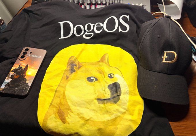A black t-shirt featuring 'DogeOS' text and a Doge graphic is displayed alongside a black cap with a gold 'D' logo and a smartphone.