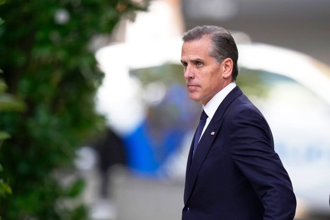 Hunter Biden, dressed in a dark suit with a small American flag pin, looks back over his shoulder in this image, which accompanies a breaking news report about his planned launch of a meme coin called $LAPTOP on September 9.